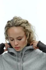 Cazadora de estilo deportivo con capucha ajustable, cierre frontal de doble cremallera y mangas abullonadas con puños elásticos. Presenta bolsillos delanteros y bajo elástico.