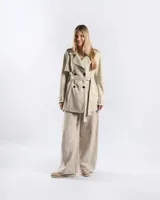 Campera trench de gabardina en color beige, con solapa cruzada, doble botonadura frontal, hombreras y cinturón ajustable para anudar en la cintura. Presenta bolsillos delanteros y puños ajustables con tiras.