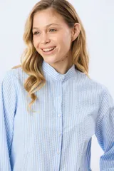 Camisa rayada de manga larga, confeccionada en algodón, con cuello mao y cierre frontal de botones.
