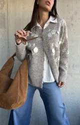 Cardigan de punto color beige con diseño de flores bordadas en relieve, cuello redondo, cierre frontal con botones y puños acanalados.