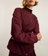 Campera rompevientos deportiva de mujer, marca Get Over, color beige con sutiles rayas verticales, cuello alto, cierre frontal con cremallera y puños ajustados.