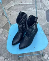 Botas estilo texanas de cuero vacuno color negro, con costuras decorativas en contraste de color blanco. Presentan punta fina y taco cuadrado de madera.