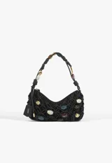 Cartera baguette Schutz de cuero negro con diseño de red trenzada y apliques de cuentas de colores y formas variadas tanto en el cuerpo como en la manija. Incluye llavero colgante con la marca grabada.