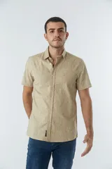 Camisa de hombre Mistral con look lino, de manga corta y corte slim. Presenta un estampado lineal de flores en color azul sobre fondo blanco, cartera abotonada y logo bordado en el pecho.