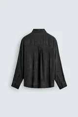 Camisa de corte relajado con diseño de cuadros en tonos negro y beige, cuello camisero, manga larga y cierre frontal de botones.