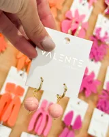 Aros colgantes dorados con bolitas rosadas.