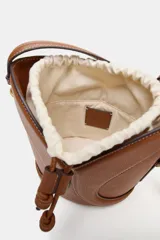 Bolso bandolera formato saca color tostado, con detalle de pespuntes decorativos en el cuerpo, cierre mediante fruncido con cordones y compartimento interior en tejido.