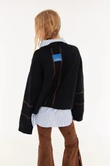 Sweater de punto color beige, con diseño de textura acanalada en mangas y espalda, cuello polo en color bordó y parche decorativo en la parte superior de la espalda.