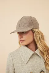 Gorra con visera confeccionada en lana fina sin teñir, con un sutil patrón de tejido en espiga.