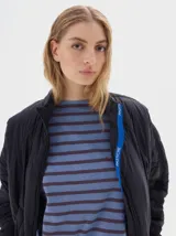 Campera marrón claro con diseño acolchado de rombos, cuello alto, cierre frontal con cremallera, bolsillos laterales y mangas largas con rayas blancas.