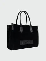 Cartera tote Balmain modelo B-Army Shopper Small, confeccionada en gamuza negra con detalles en cuero negro liso. Cuenta con doble asa superior, ribetes pespunteados y un parche frontal de cuero con el logotipo grabado en relieve.