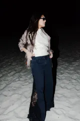 Jean de denim negro de corte wide leg, con paneles laterales de encaje negro mate a lo largo de las piernas.