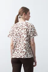 Remera de manga corta con estampado animal print en tonos blanco, marrón, beige y celeste.