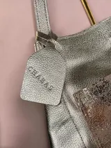 Bolso tipo tote Chabas confeccionado en cuero genuino color plateado, con un bolsillo frontal texturizado en tonos metalizados y doble asa superior para el hombro.