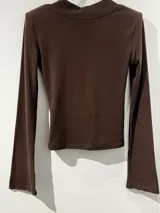 Remera de manga larga color negro, con escote en V y mangas acampanadas tipo Oxford. Confeccionada en tejido de algodón elastizado, con un diseño entallado al cuerpo.