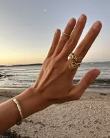 Brazalete rígido abierto de metal color plateado con textura irregular.