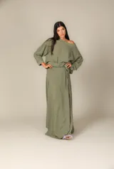 Blusa holgada color verde oliva, con escote amplio que puede usarse caído sobre un hombro, mangas largas y puños ajustados.