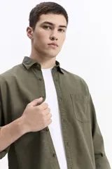 Camisa de manga larga color azul marino con textura, cuenta con cuello clásico, cierre frontal con botones y un bolsillo en el pecho.