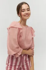 Blusa color rosa pálido de algodón con mangas cortas abullonadas y volados en el escote.