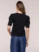 Remera de algodón negro, de silueta semi entallada, con escote redondo y mangas cortas abullonadas al codo con frunces en los hombros.