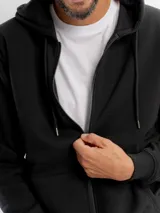 Campera de felpa negra con capucha, cierre frontal completo y bolsillos laterales. Diseño liso con puños y ruedo acanalados.
