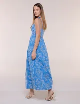 Vestido midi color azul con bordado broderie floral en tono blanco, escote recto con tirantes finos de lazo para anudar, corte ajustado en la cintura y falda escalonada holgada con bolsillos laterales.