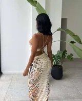 Vestido midi con estampado de piel de serpiente en tonos beige y marrón. Diseño con top halter y falda tubo con abertura lateral.