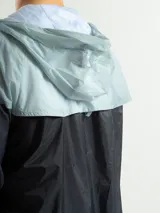 Campera deportiva negra de nylon impermeable con capucha y cierre frontal. Presenta puños y cintura elásticos de tejido acanalado. Tiene un pequeño logo blanco en el pecho.