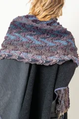 Capa artesanal combinada en texturas de color negro y gris con aplique de chal y dos bolsillos.