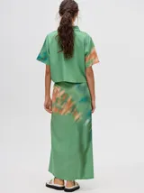 Falda midi tipo pareo color verde con estampado estilo tie-dye en tonos azul, naranja y blanco, con tiras ajustables en la cintura.