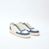 Zapatillas bajas de estilo deportivo, con capellada bicolor en blanco y azul. Presentan paneles superpuestos de material sintético, puntera perforada, cordones color crema y suela de goma color beige.