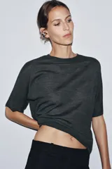 Jersey de punto liso color gris oscuro, con cuello redondo y mangas cortas amplias.