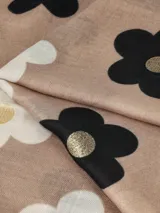 Bufanda negra con estampado de flores en tonos beige y marrón, con centros dorados.