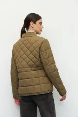 Campera capitoneada color beige, de cuello alto, con bolsillos de solapa y botones metálicos.