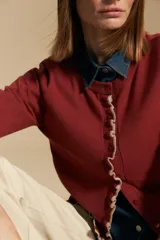 Cárdigan beige de manga larga, tejido liviano y suave, con volados en el delantero, ruedo y puños. Cierre frontal con botones.