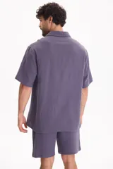 Camisa de muselina de manga corta color beige, con cuello camisero y cierre frontal de botones.
