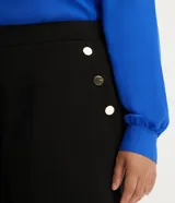 Bermuda de crepé color blanco, de corte holgado y tiro alto, con pliegues frontales y bolsillos laterales con detalle de botones. Confeccionada en poliéster y elastano.