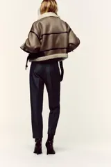 Pantalón de tiro alto y corte tobillero, confeccionado en tejido de aspecto denim oscuro. Presenta diseño de pinzas frontales, bolsillos laterales y cierre frontal con cremallera, botón y gancho. Incluye un cinturón fino a tono con hebilla metálica dorada.