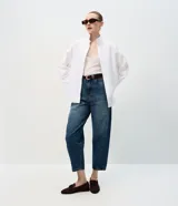 Pantalón de jean con corte new carrot, de cintura alta y estructura firme. Presenta un lavado azul oscuro uniforme, con volumen en la cadera y piernas que se afinan hacia el bajo. Incluye presillas anchas, cierre frontal con botón y cremallera, y bolsillos funcionales.