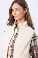 Chaleco de cuello alto con cierre frontal, confeccionado en tejido de poliéster con textura tipo lana, en color beige.