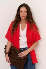 Sobrecamisa roja de lino de manga corta, con cuello solapa, costuras decorativas en contraste y cierre frontal con presillas y botones alargados.