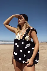 Tote bag de algodón color negro con estampado de lunares blancos. Cuenta con doble asa de hombro y etiqueta frontal con el logo de la marca.