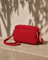 Bandolera roja de nylon impermeable con tres compartimentos principales con cierre, correa regulable y herrajes metálicos dorados.