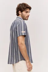 Camisa de manga corta color azul con diseño a rayas verticales, cuello clásico y cierre frontal de botones.