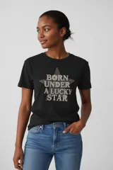 Remera negra de manga corta y cuello redondo, con estampado frontal en forma de estrella que incluye la frase 'Born under a lucky star' decorada con strass.