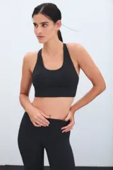 Top deportivo negro de escote redondo y espalda estilo nadadora, con banda elástica inferior para mayor soporte.