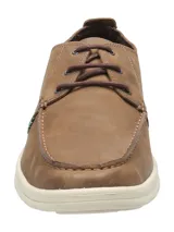 Zapato casual tipo náutico de cuero marrón con cordones, suela de goma blanca y costuras visibles. Cuenta con el logotipo de la marca grabado en el lateral.