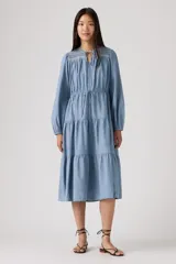 Vestido midi de color azul, con diseño de volados en la falda, mangas largas con puños, escote con cordón ajustable y detalle de bordado en la parte superior.