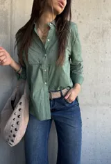 Camisa de manga larga color verde militar, con cuello camisero, cierre frontal de botones y detalles de bordados y calados en el frente y las mangas.