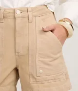 Short mom de tiro alto confeccionado en sarga de algodón, con diseño de bolsillos tipo carpintero en la parte frontal, cierre de botón y cremallera, y trabillas en la cintura.